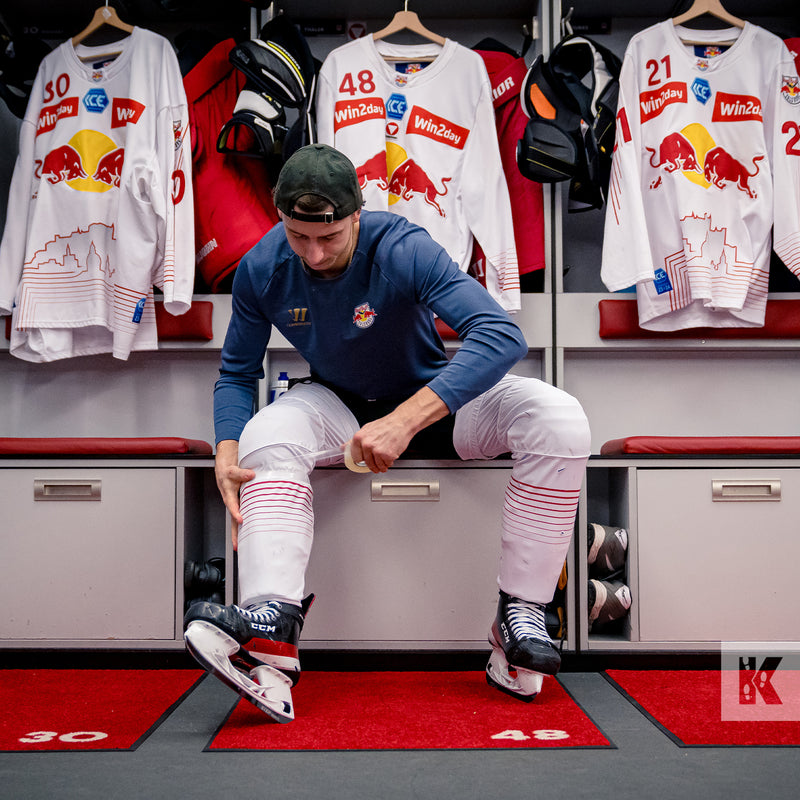 Jet-Print Light - Locker room mats that identify the position number of each Hockey team player, reflected in the team shirts hung up in the background