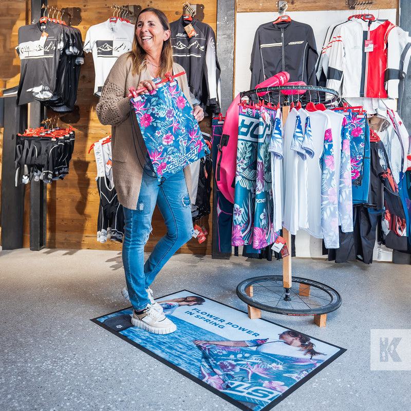 Jet-Print Patio - Lady browses products while standing on a mat with in-store graphics to accompany a clothes display rail