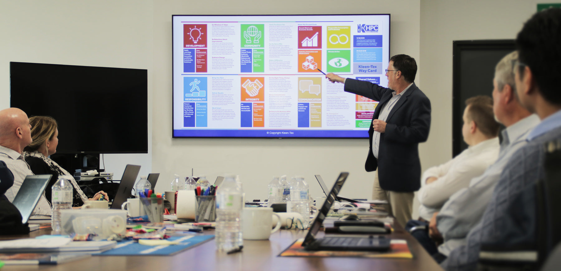Kleen-Tex HPC meeting, speaker points to large screen with graphics