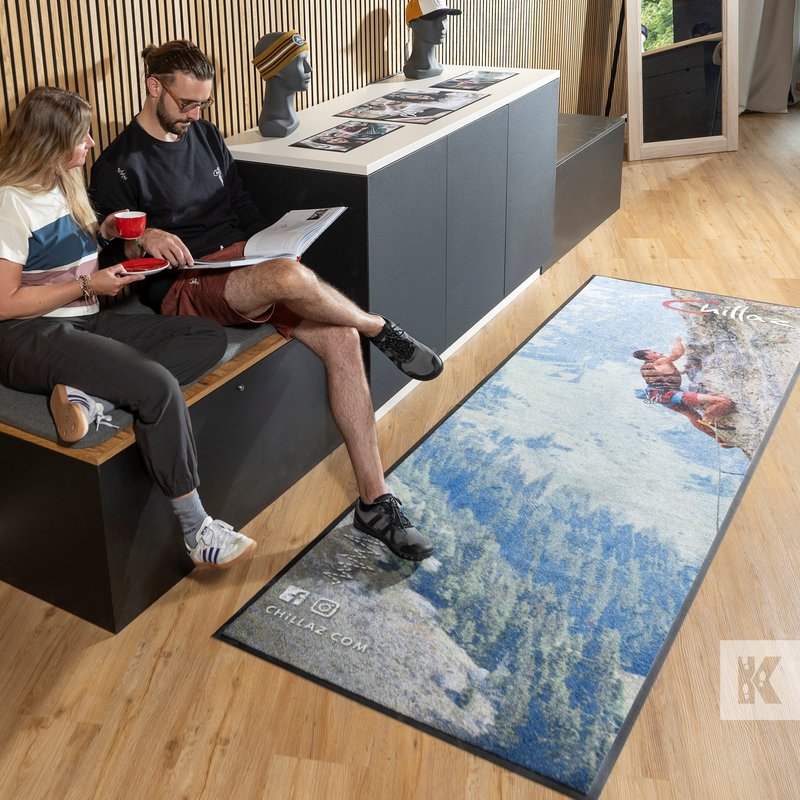 Two people sitting on a bench with a decorative mat featuring a nature scene in the foreground.