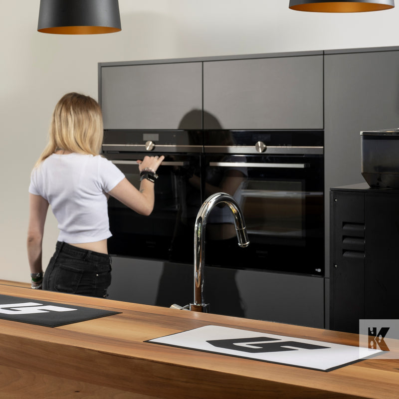Bar-Mat - Mats on a kitchen counter top with a young lady operating an oven in the background