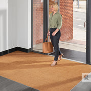 Coir-Mat - Lady entering building and walking across a plain natural mat fitted in a recess