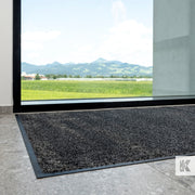 Green-Horse - Entrance mat in front of a glass door, looking out onto a green field area