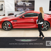Jet-Print Mat - Aston Martin branded mat in front of a super cool red Aston Martin