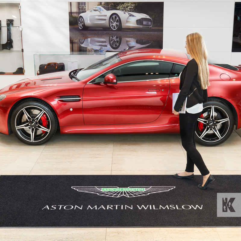 Jet-Print Mat - Aston Martin branded mat in front of a super cool red Aston Martin