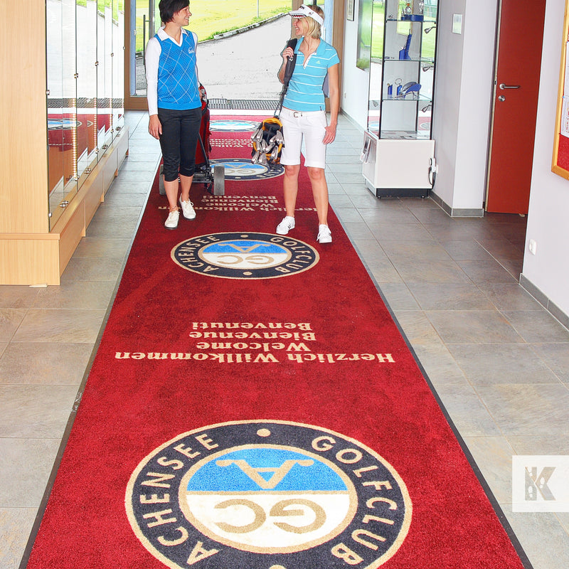 Jet-Print Horizon - Two young ladies in a golf club corridor on a long printed red mat with display cabinets