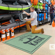Jet-Print Light - A man kneels in front of a Kayak display to browse products, a large green Kayak branded mat is in the foreground