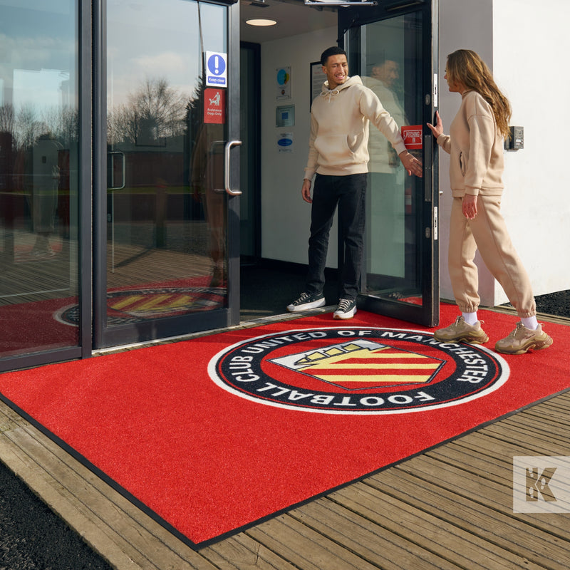 Jet-Print Outdoor - Welcome to Football Club United of Manchester a couple enter the sports facility with a bright outdoor mat at the entrance
