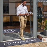 Jet-Print Outdoor - Man walking out of a store with a pamphlet, crossing a Havwoods branded outdoor mat