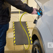 Kleen-Cable Mat EV - Man charging a white car with the cable running under a mat