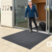 Man exiting a building with a suitcase on a doormat